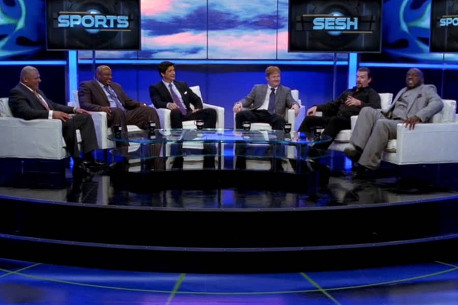 6 men in comfy chairs chatting sports