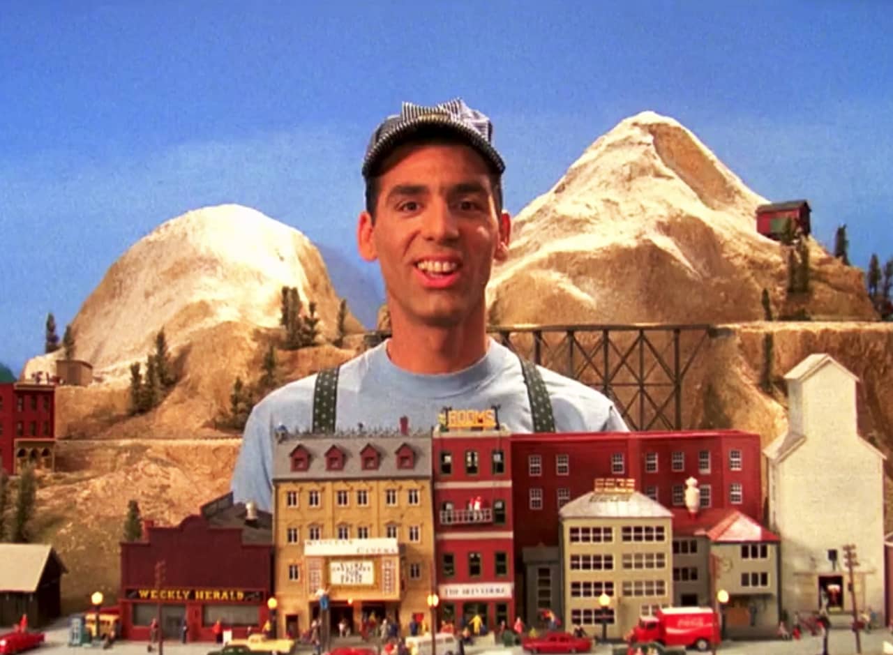 Stanley Spadowski in front of a miniature mountain and model train and town
