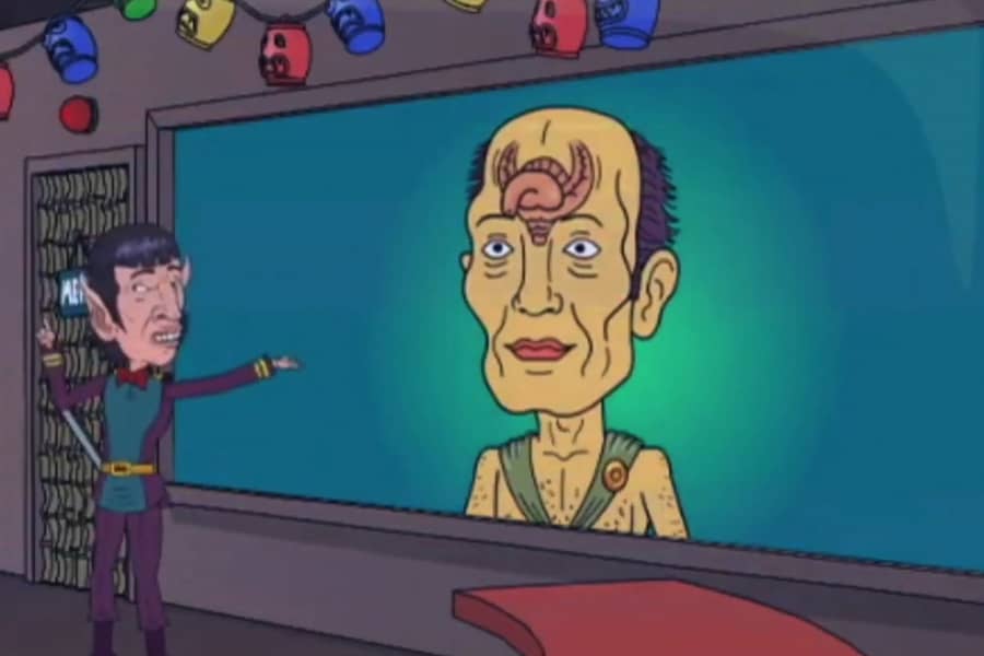 Gayspock pointing at a big screen showing an alien with a penis on his forehead