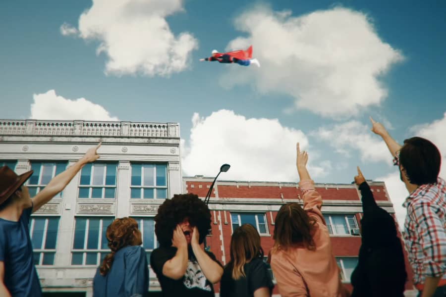 kids in a schoolyard point up at him in the sky
