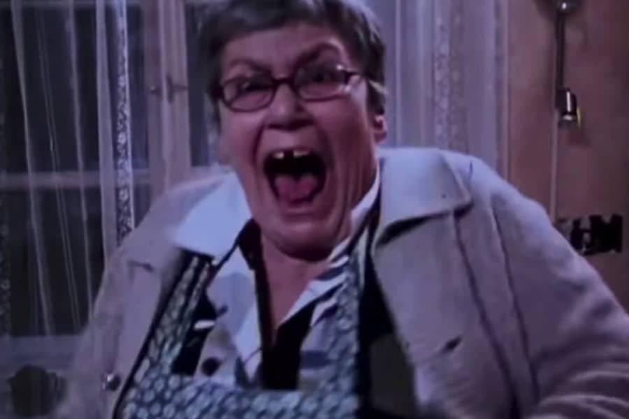 an older woman in an apron screams in fear
