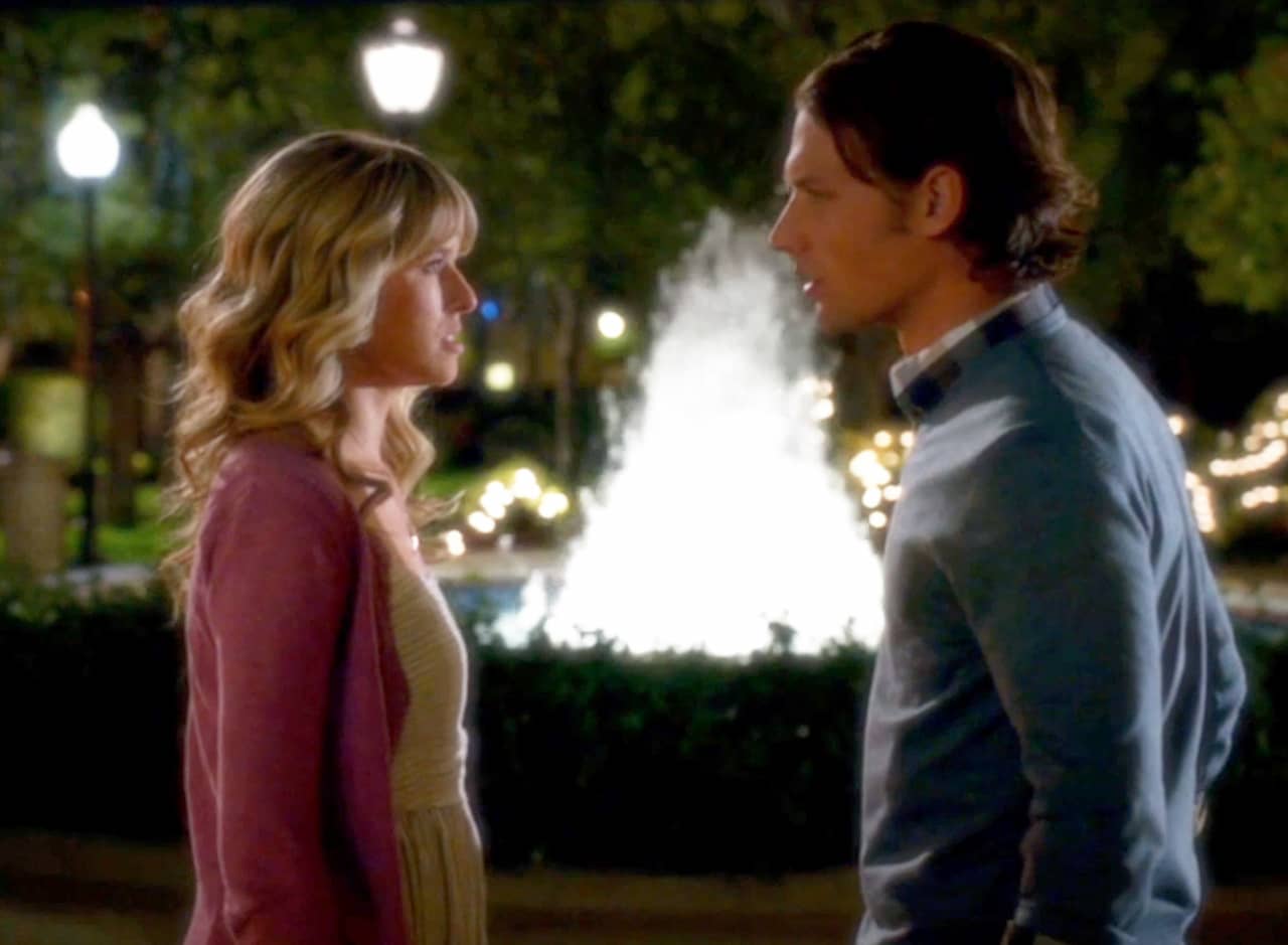Nicki and Nick look at each other in front of a fountain