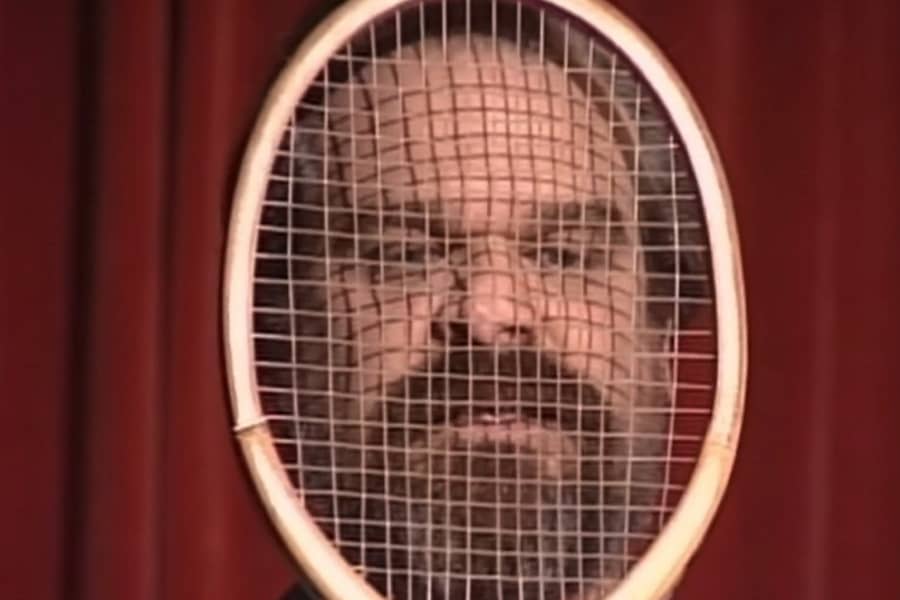 actor David Harbour Jr. peering through a tennis racquet