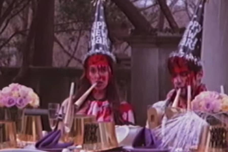 the two teens at the table wearing party hats, covered in blood