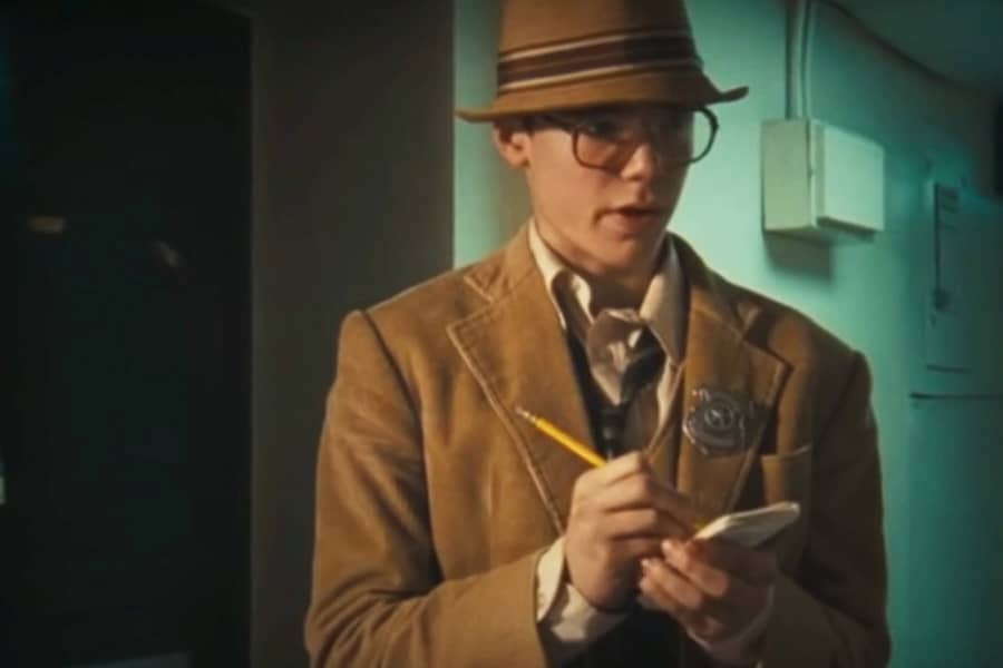 teen boy dressed as an investigator taking notes on a pad of paper