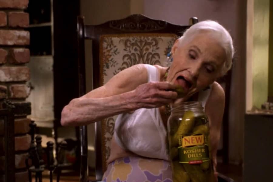 a grandma in her brassiere eats pickles out of the jar