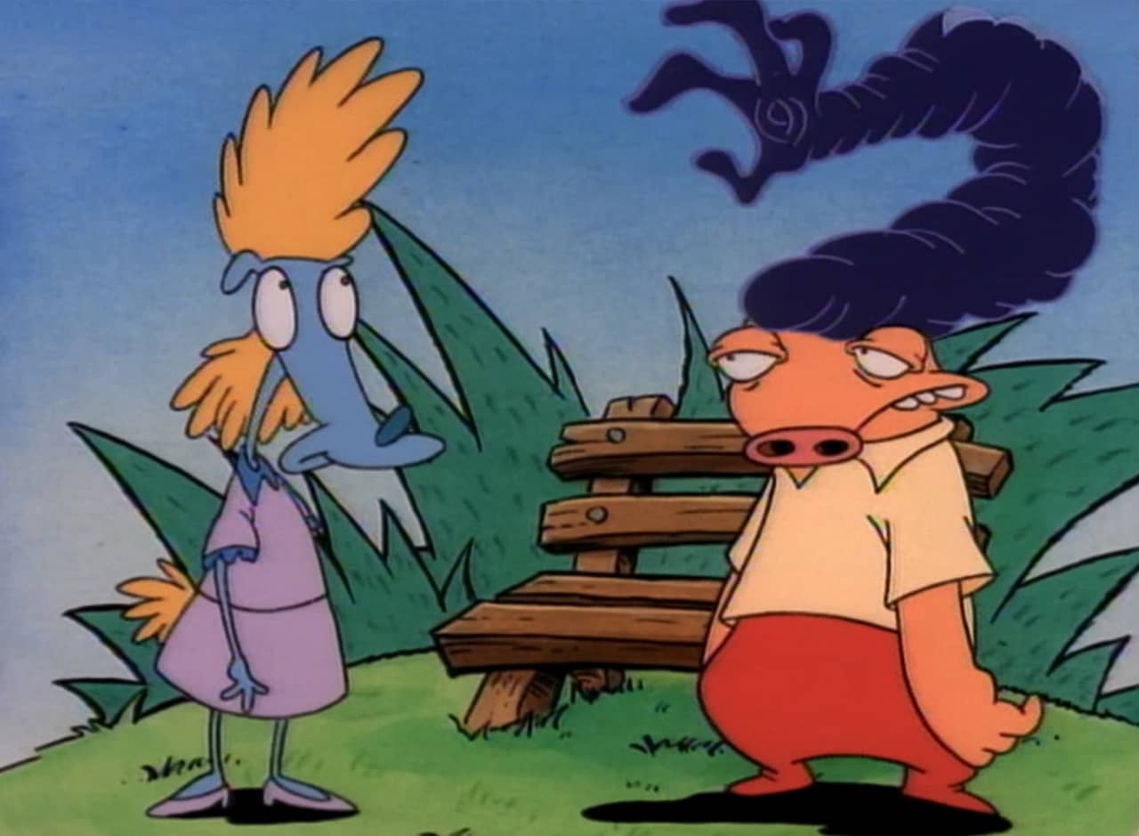 a woman stands by a man in the park, his huge hair making the shape of hand