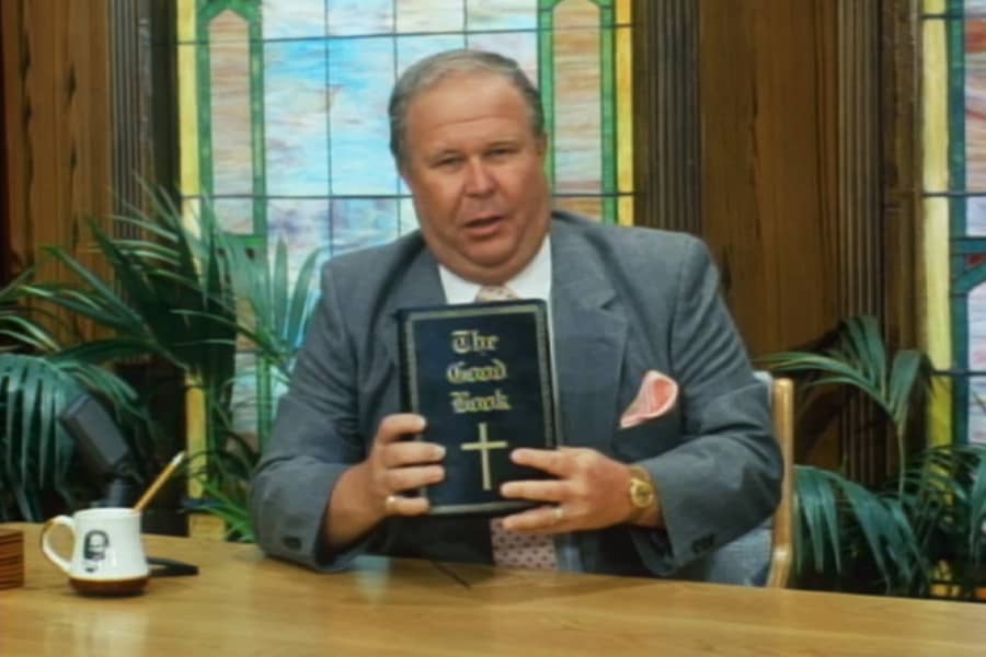 Ernest sitting at a desk and holding a Bible