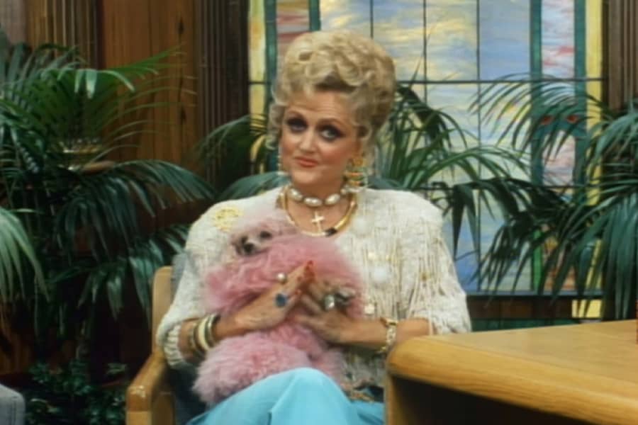 Fanny Ray sitting and holding a pink miniature poodle