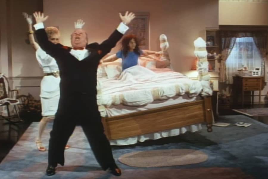 Ernest and Fanny Ray dancing with arms raised as a possessed woman is tied to a bucking bed