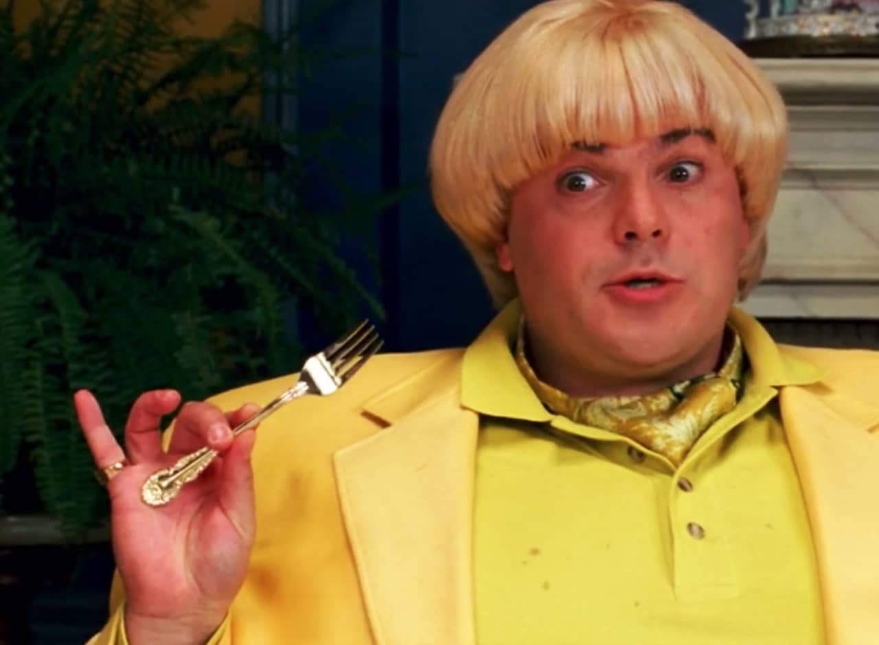 Jeff Portnoy holding a fork, wearing a bright yellow suit with a dorky blonde bowl cut