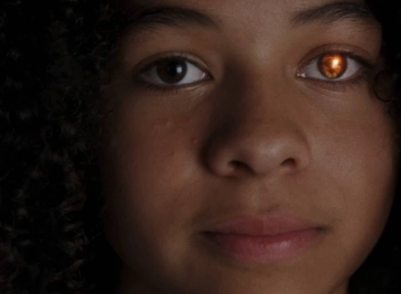 a young black girl with one glowing, gold eye