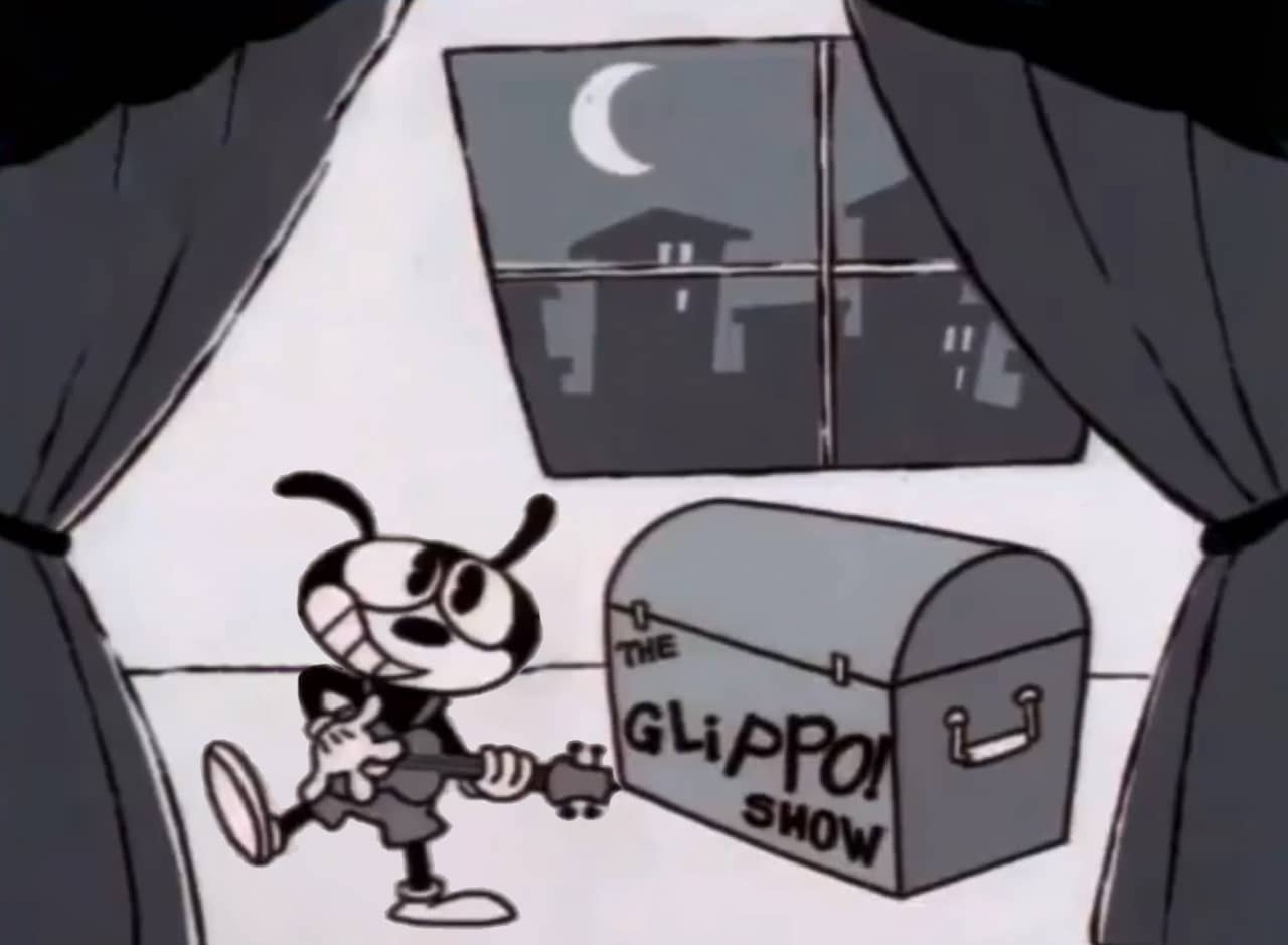 Glippo, a cartoon rabbit, playing a guitar next to a trunk