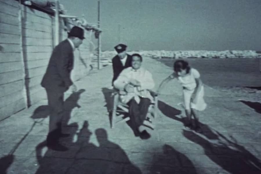 man in a chair with a woman nearby on a pier
