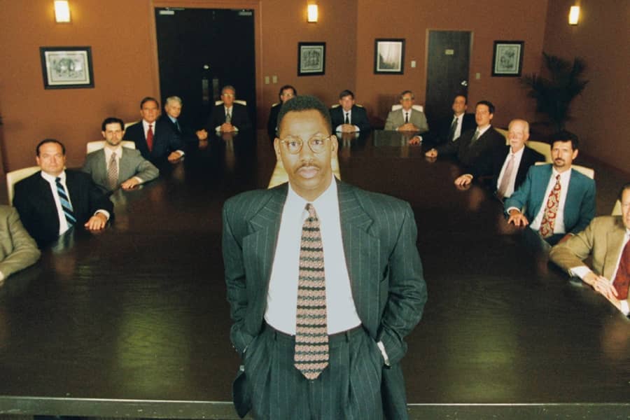 Washington in a suit in front of a boardroom