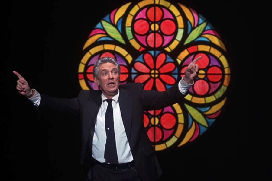 Howard Beale speaking in front of a stained glass window