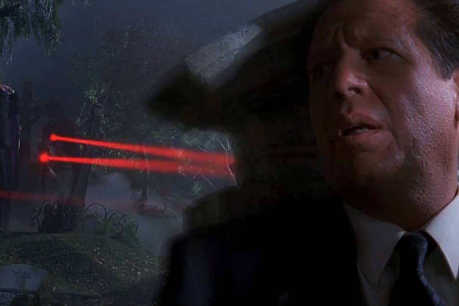 Mulder hides behind a headstone while rifle lasers point at him