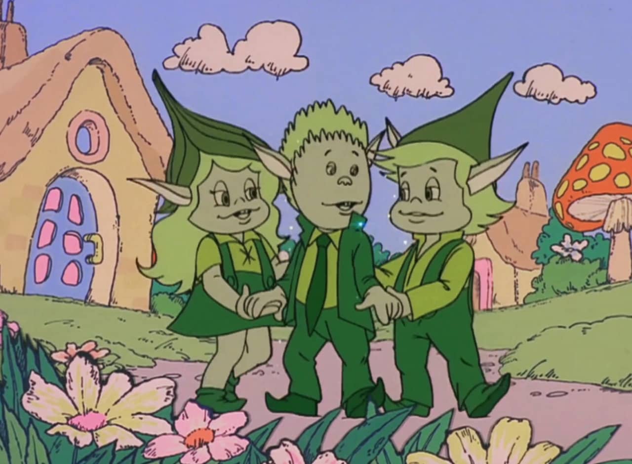 three green elf-like beings, The Likeables, in a miniature storybook village
