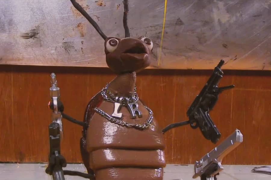 little roach wearing chains and holding four guns