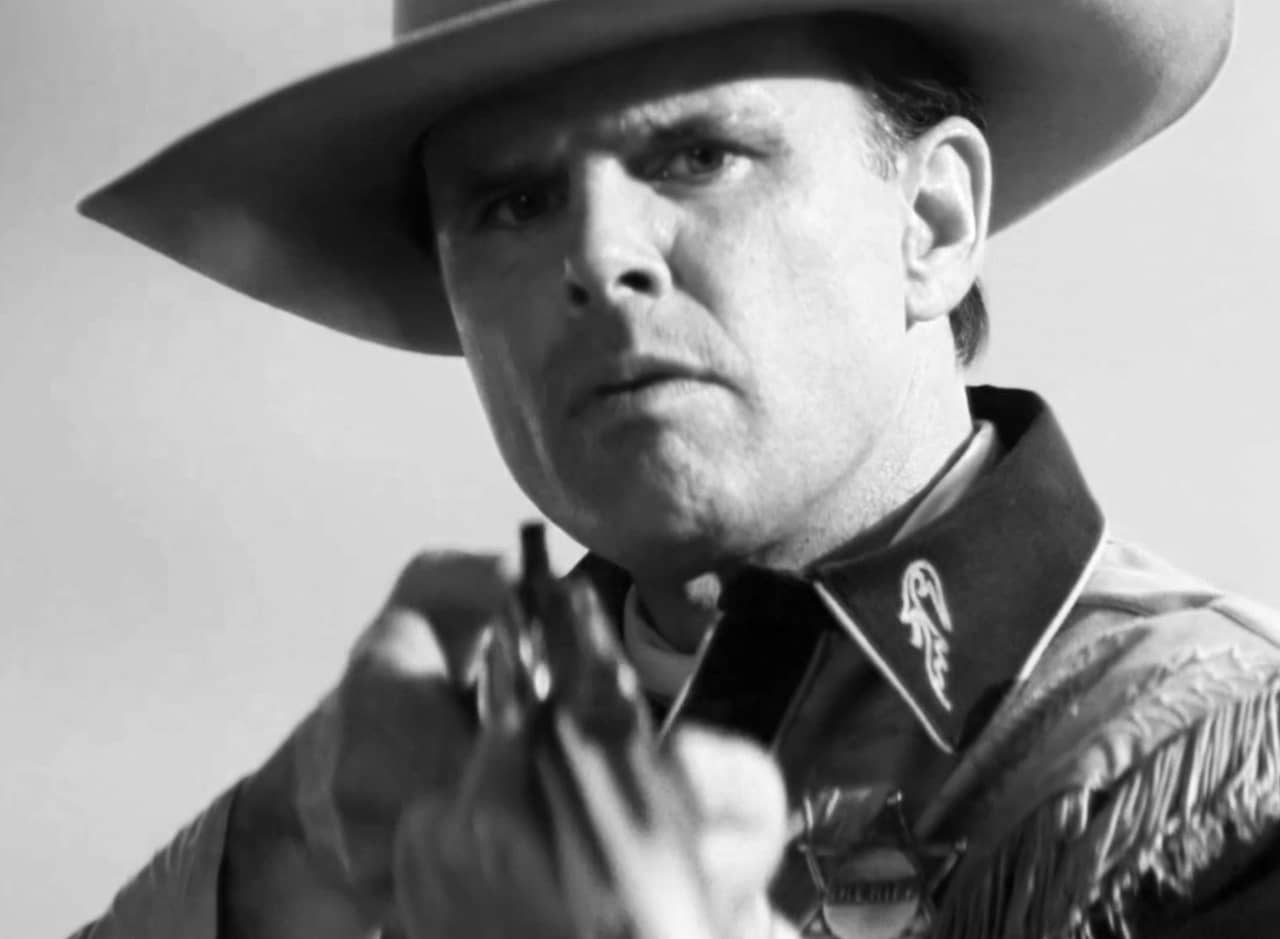 Cooper Howard as a cowboy pointing a gun