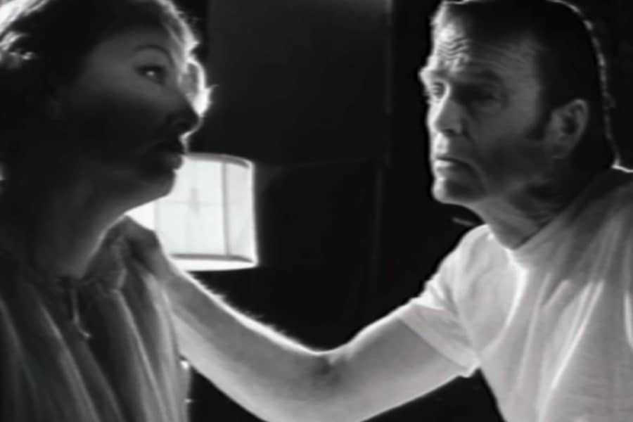 man talks with a woman, his arm is on her shoulder