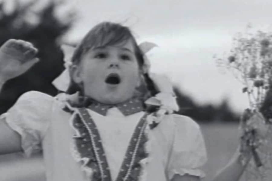 little girl looks shocked, holding a bouquet of wild flowers