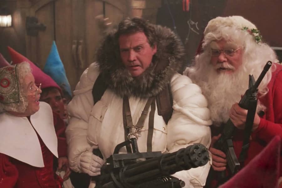 Lee Majors holds a gatling gun and talks with Santa and Mrs. Claus