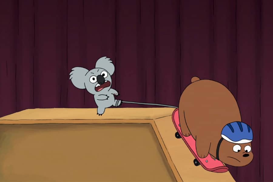 Grizz the bear riding down a ramp on a skateboard, Nom Nom’s leg is tethered to the board as he realizes and screams