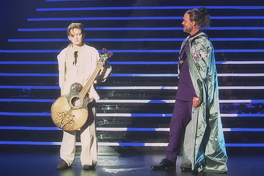 Plutonovich on stage with O’dessa who is holding a guitar