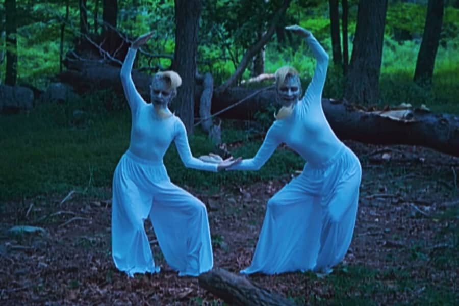 two creepy people dressed all in white dance in the woods