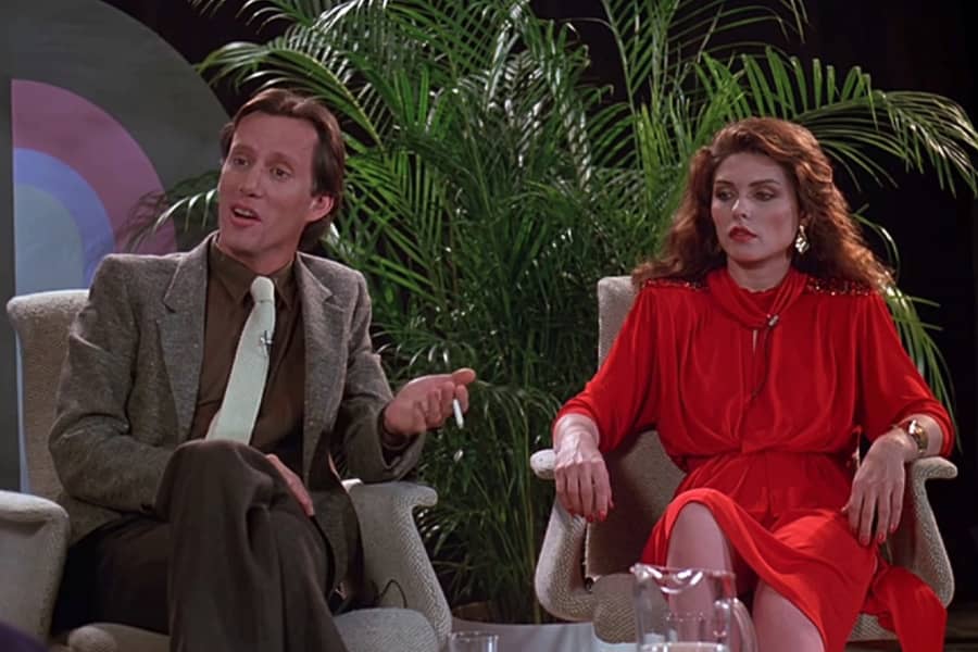 two guests: Max Renn (a man in a suit) and Nicki Brand (a blonde woman in a red dress)