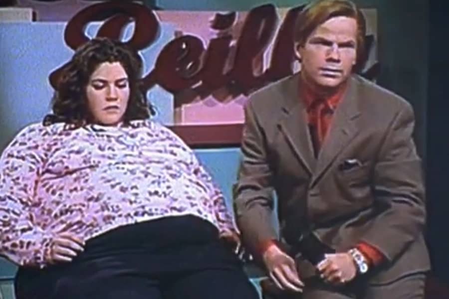 Rex Reilly sitting awkwardly next to a fat woman