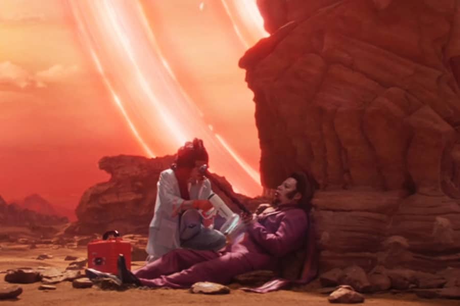 a medic crewmember helps an impaled Friess on a desert planet