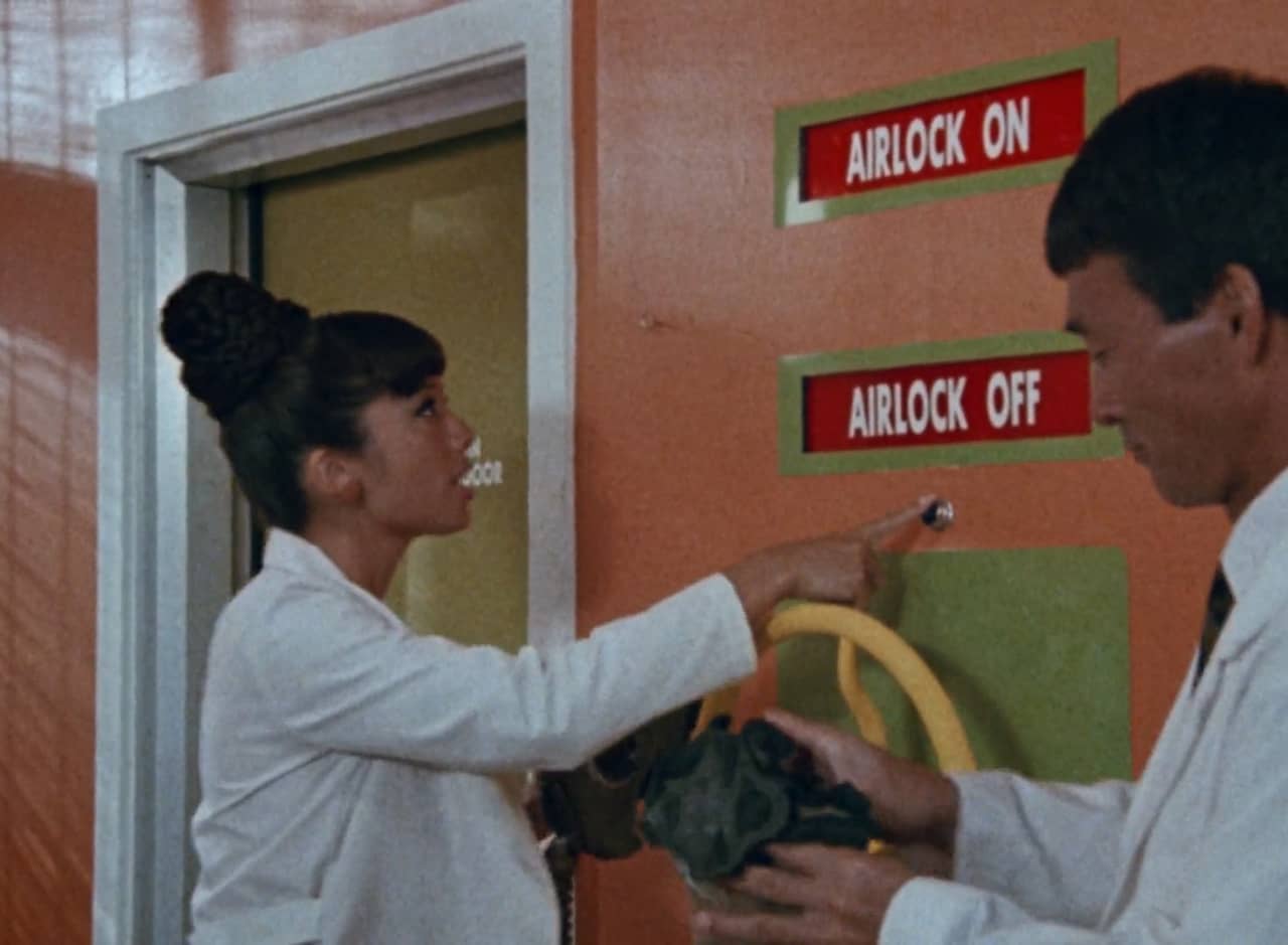 woman in lab coat pushing an “airlock off” button