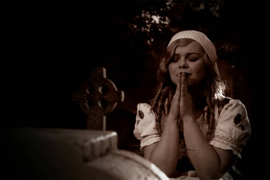woman praying at a gravestone