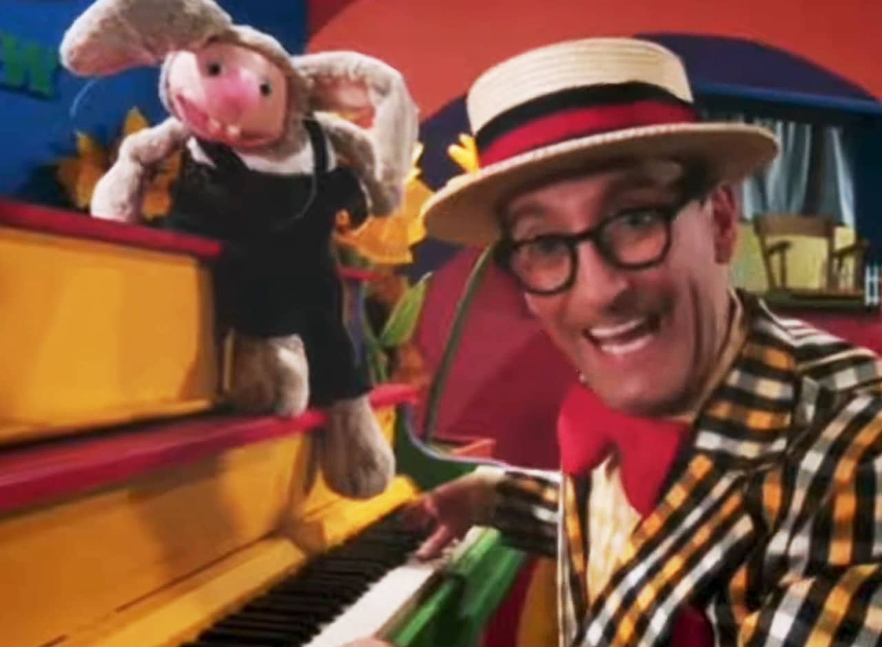 Uncle Howee, man with glasses, plaid jacket, and red bowtie, at the piano with his puppet rabbit friend Loomis