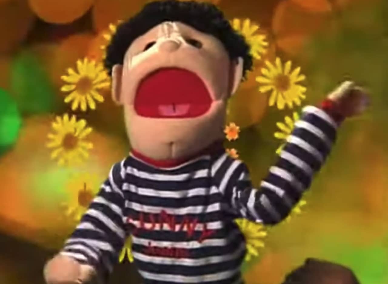 a puppet of a boy in a striped shirt in front of a psychedelic background