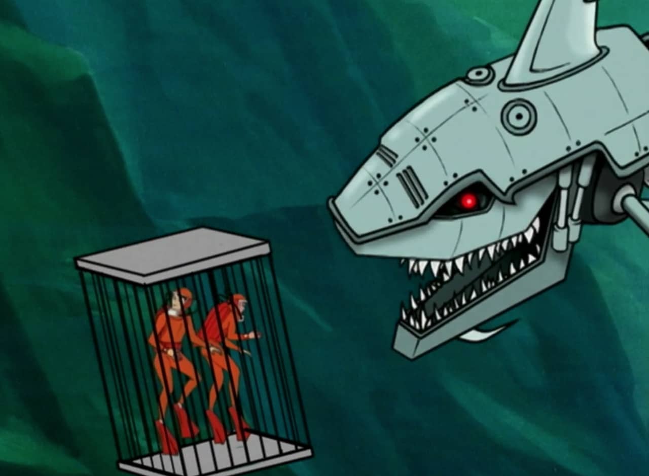 a big robot shark approaches two divers in a cage
