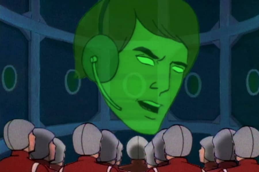 a green hologram head speaks to a group of soldiers