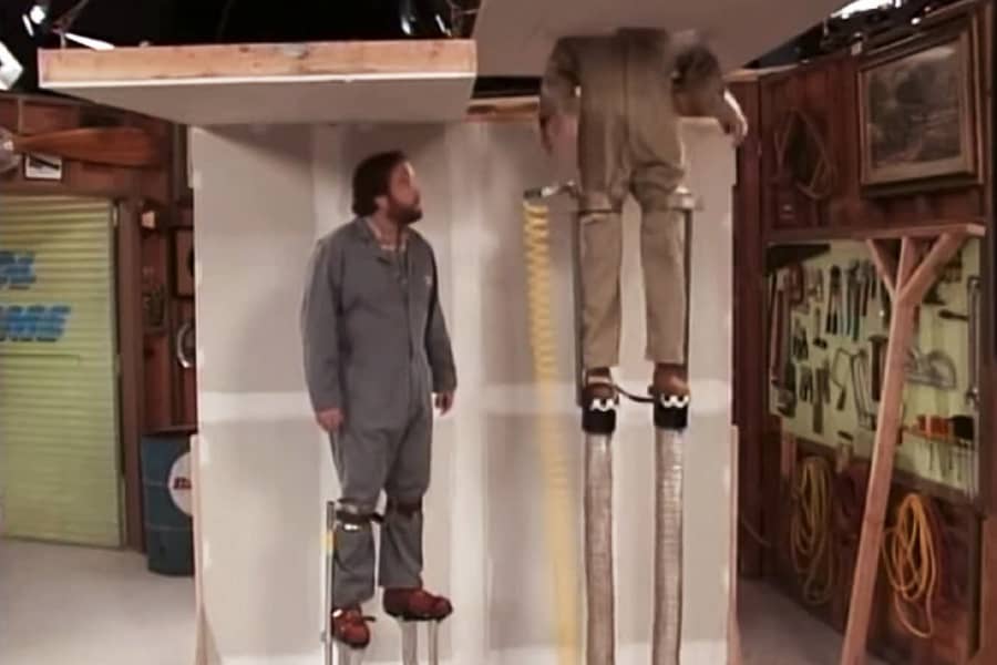 Al and Tim are wearing powered stilts and Tim has shot through the fake ceiling