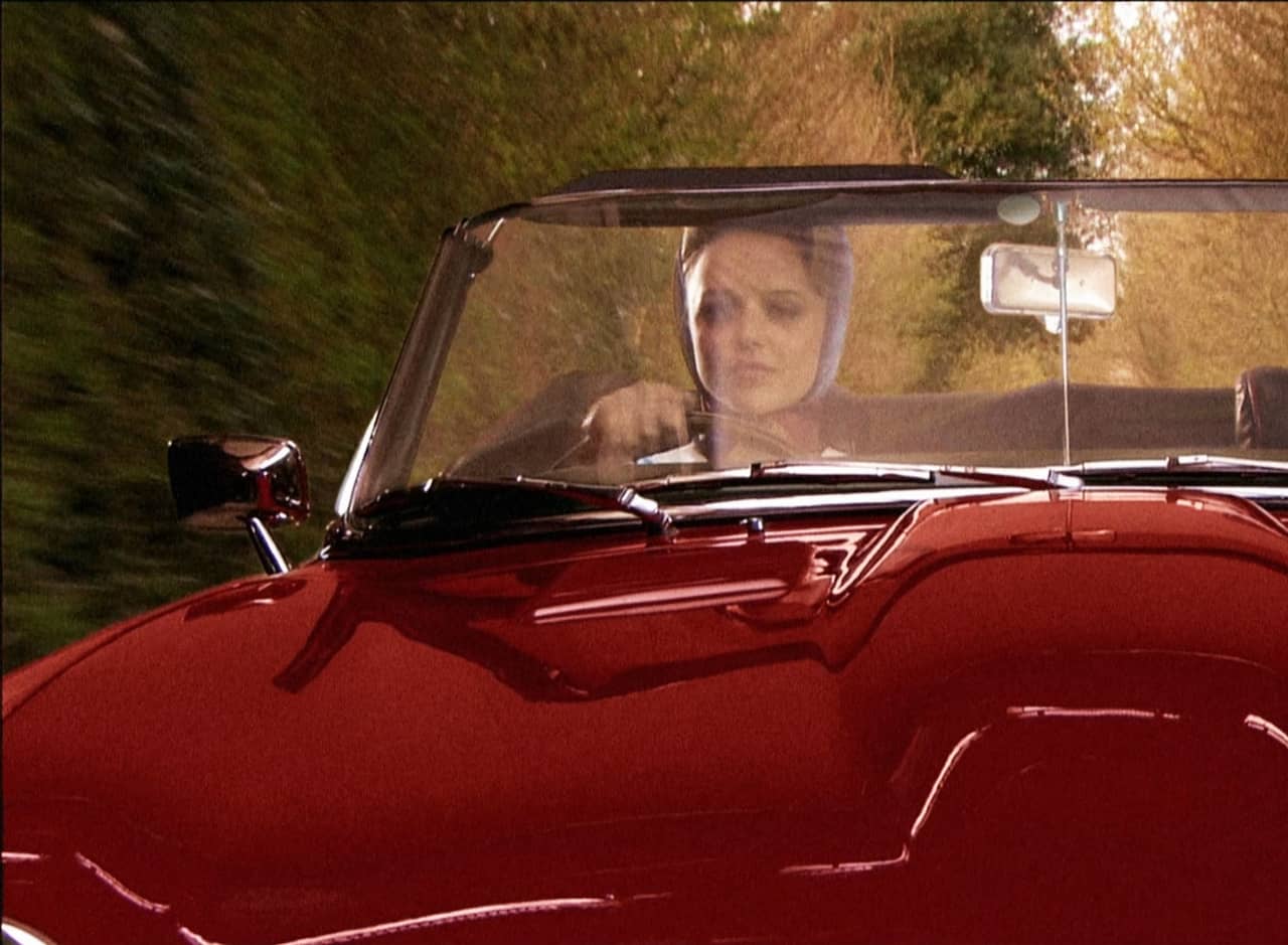 Stella Harris driving a red convertible
