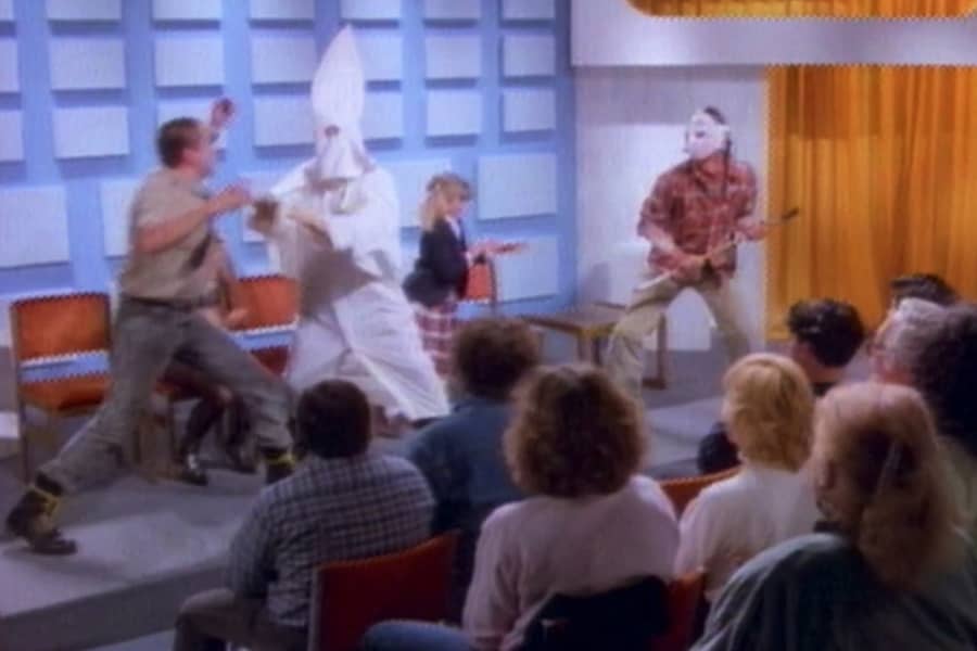 people brawling on stage including a KKK guy, a guy in a hockey mask, and a little school girl