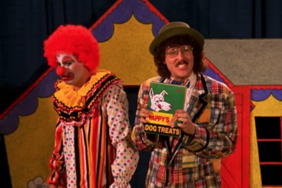 George with a clown and holding dog treats