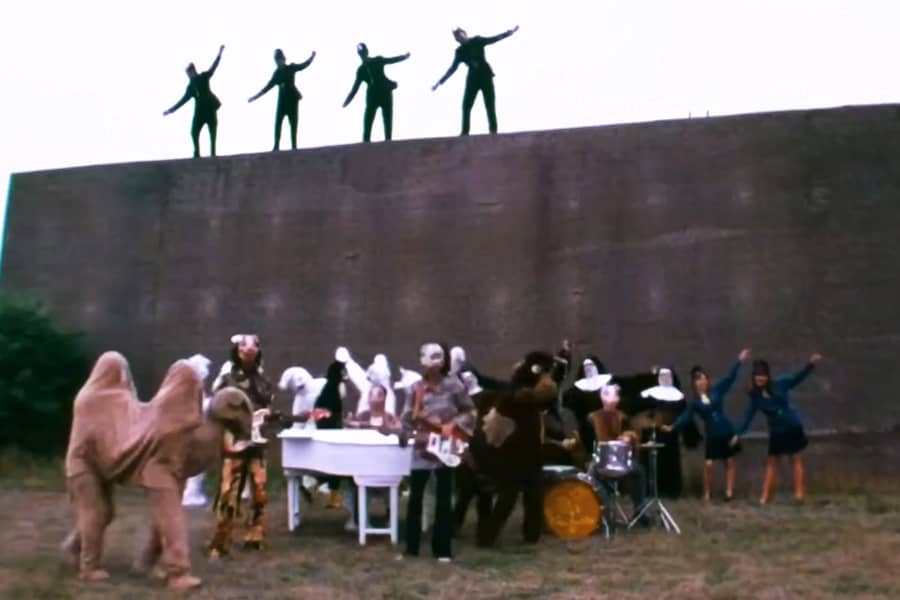 the band performing with lots of weird people dancing around them