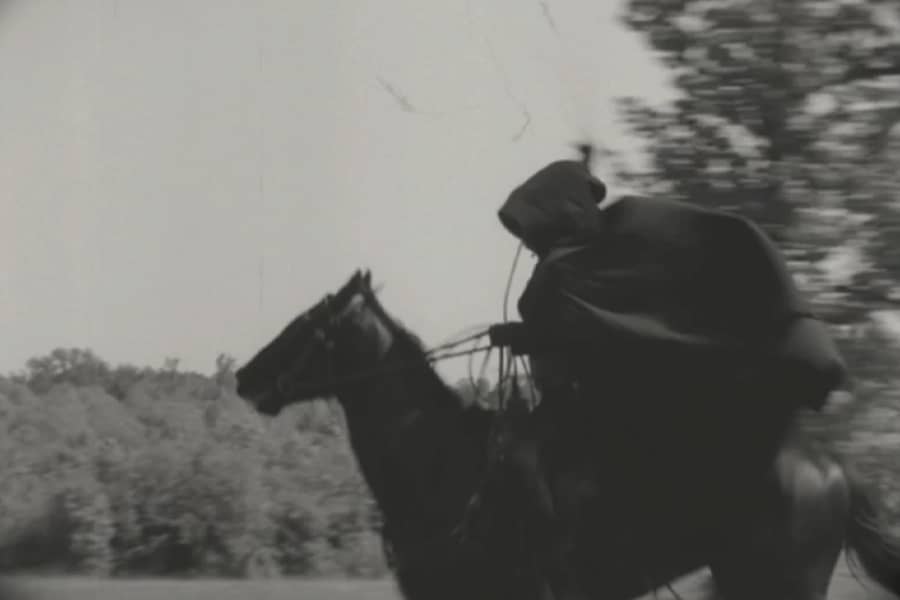 a hooded person rides a horse