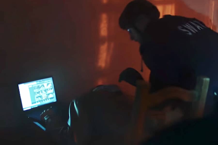 SWAT officer looking at a computer with surveillance footage