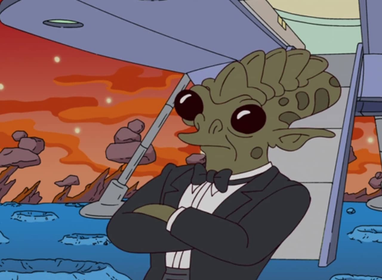 an alien named Trey in a tuxedo stands cross-armed in front of his spaceship