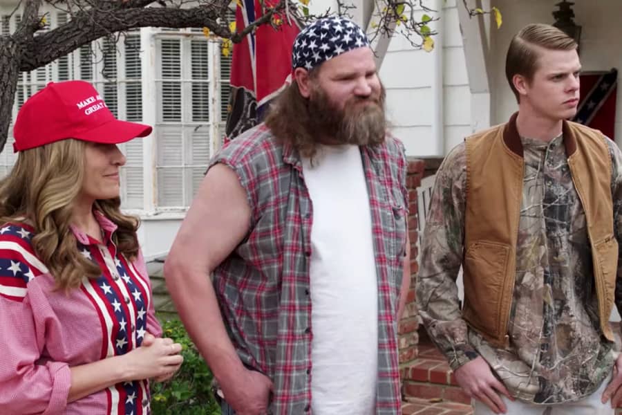 two white men and a woman wearing ratty clothes, Trump hats, and American flag paraphernalia