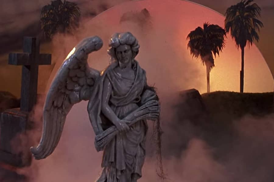 graveyard angel statue in front of palm trees