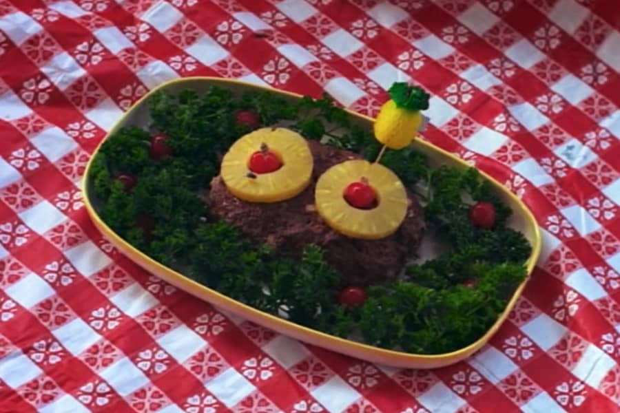 a meatloaf type dish garnished with pineapple on a picnic table